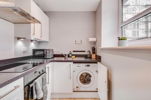 a white kitchen with a washing machine and a window at Modern Living Stevenage 1 bed apartment Town Centre Tesco at Doorstep up to 4 people in Stevenage