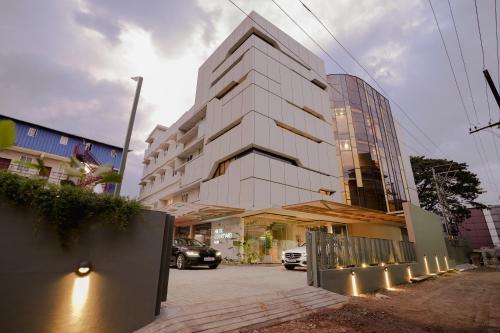a white building with a car parked in front of it at HILUX COURTYARD in Palakkad