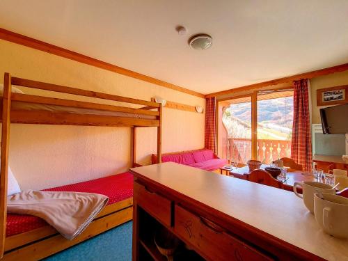 a room with two bunk beds and a table at Appartement 2 pièces ski aux pieds avec balcon - 4 personnes - FR-1-344-940 in Les Bruyères