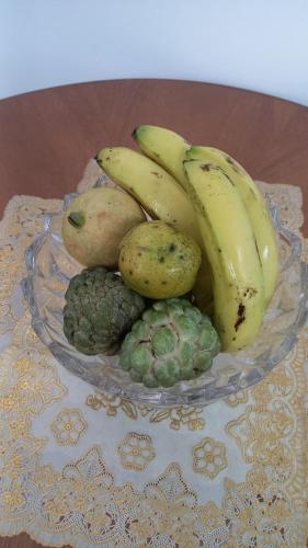 a glass plate with bananas and other fruits on a table at Cozy vacation retreat with free parking in Roseau