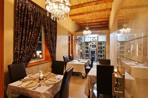 a dining room with tables and chairs and a chandelier at Surval Boutique Olive Estate in Oudtshoorn