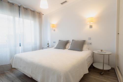 ein weißes Schlafzimmer mit einem weißen Bett und einem Fenster in der Unterkunft AZZ Sevilla Torre de la Plata Apartamentos in Sevilla