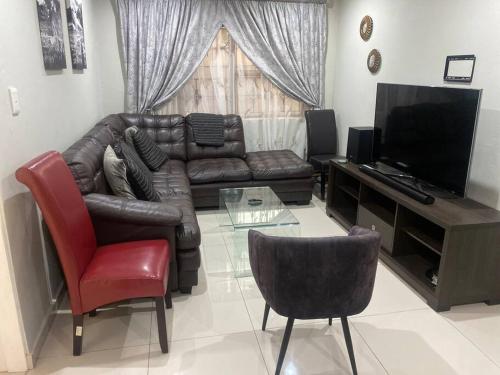 a living room with a leather couch and a television at One Bedroom Luxury Apartment in Pretoria