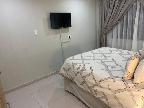 a bedroom with a bed and a flat screen tv at One Bedroom Luxury Apartment in Pretoria