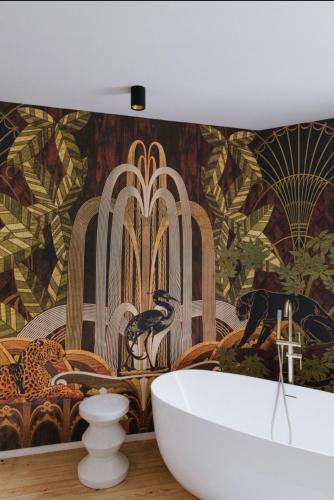 a bathroom with a bath tub and a wall mural at Au Numéro 5 in Tilff