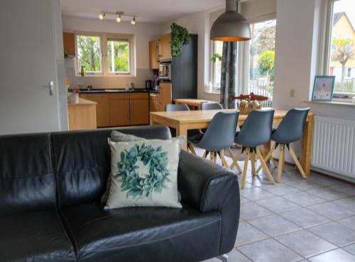 a living room with a black couch and a kitchen at Huisje 11 Wemeldinge in Wemeldinge