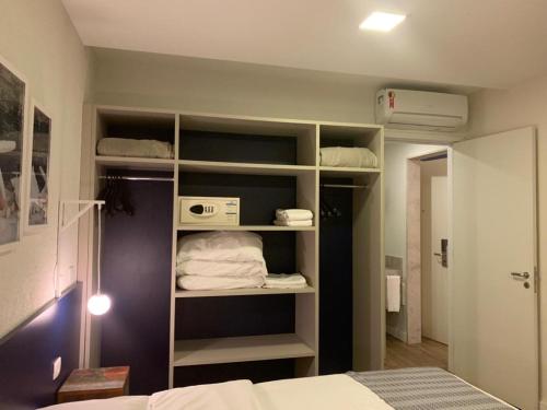 a room with a bed and a closet with shelves at Apartamento em Resort Angra dos Reis in João Neiva