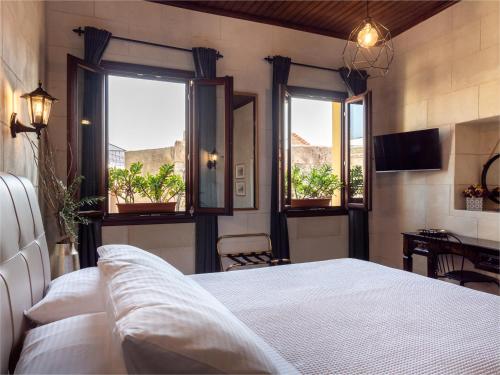 a bedroom with a bed and two windows and a table at Casa Theano - Old Town in Rhodes Town