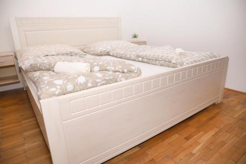 a white bed in a room with a wooden floor at Ubytovanie Viktória in Dunajská Streda