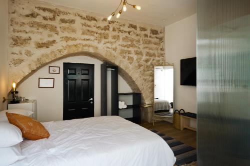 1 dormitorio con 1 cama grande y pared de piedra en Tel-Aviv LALA Boutique Hotel, en Tel Aviv