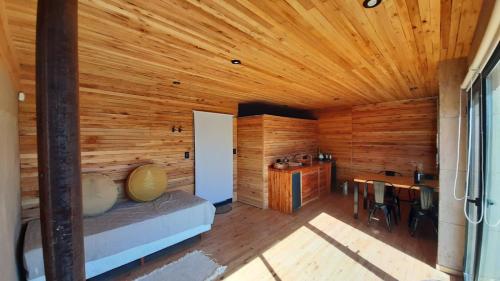 Habitación de madera con cama y mesa en La Calma Ecolodge en Las Heras