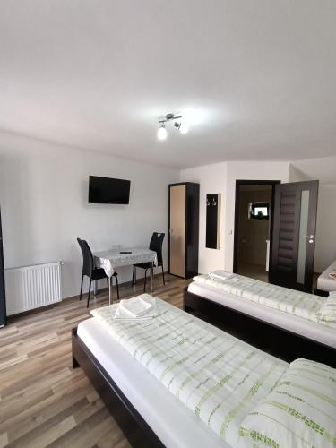 a room with two beds and a table and chairs at VILA GE in Sebeş