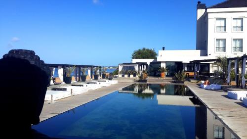 una piscina con sillas blancas y un edificio en Serena Hotel - Punta del Este - Unico sobre la Playa, en Punta del Este