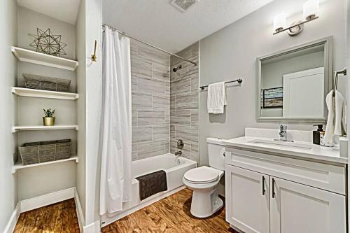 a white bathroom with a tub and a toilet and a sink at The Rhythm Room Near Downtown Dallas! in Dallas