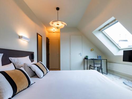 a bedroom with a large white bed with a skylight at MOKA Hôtel in Lorient