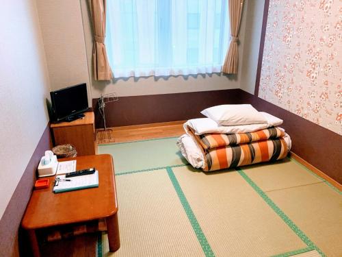 una piccola camera da letto con un letto e un tavolo di Hakodate Hotel Ekimae - Vacation STAY 91829v a Hakodate