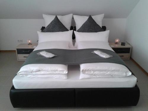 una camera da letto con un letto grande con cuscini bianchi di DZT-Schwarzwaldhotel garni a Unterkirnach