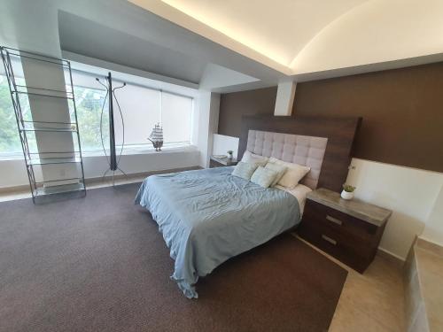 a bedroom with a bed with a nightstand and windows at Hermoso Loft espectacular vista BosquesdelasLomas in Mexico City