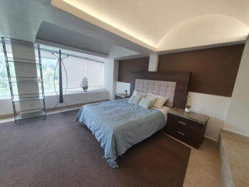 a bedroom with a bed with a nightstand and two windows at Hermoso Loft espectacular vista BosquesdelasLomas in Mexico City