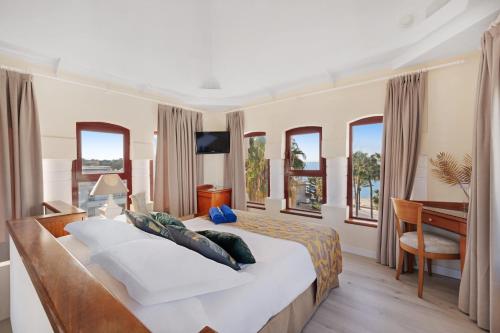 a bedroom with a bed and a desk and windows at Hotel Ciutat Jardi in Palma de Mallorca