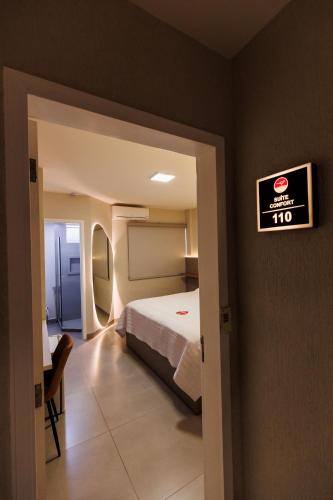 a hotel room with a bed and a sign on the wall at Tonello Business Hotel in Campo Mourão