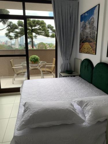 um quarto com uma cama e uma varanda com uma mesa em Estúdio Lindíssimo com Varanda! em Curitiba
