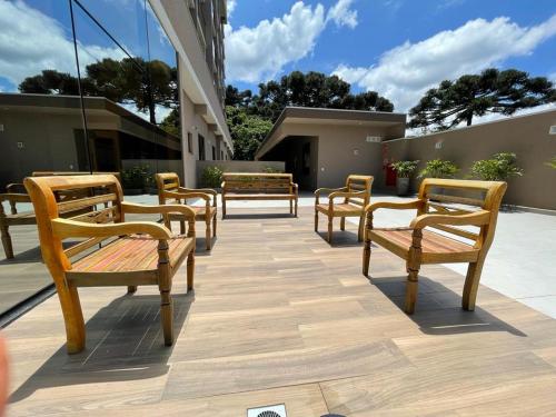 a row of wooden benches sitting on a patio at Estúdio Lindíssimo com Varanda! in Curitiba