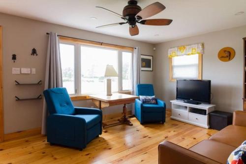 ein Wohnzimmer mit blauen Stühlen, einem Tisch und einem TV in der Unterkunft Steps to Lake on the Mountain - License ST-2020-0324 R1 in Picton