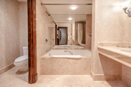 a bathroom with a bath tub and a toilet at Chateau Merrimack Hotel & Spa in Tyngsboro