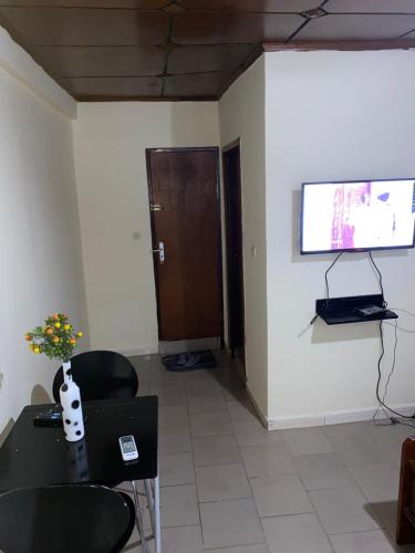 Zimmer mit einem Tisch, Stühlen und einem TV in der Unterkunft Studio meublé à Conakry in Conakry