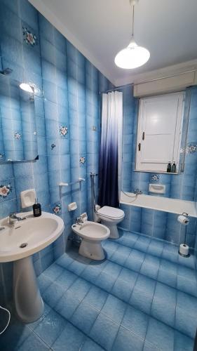 La salle de bains est pourvue de carrelage bleu, de toilettes et d'un lavabo. dans l'établissement Holiday home Nicla, à Rosolini