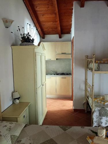 a room with a kitchen and a room with a bed at Donnigheddu in Rudalza