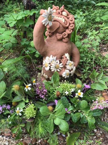 a statue in the middle of a garden with flowers at Travelers House おーさんてぃん青空舎 in Taketomi