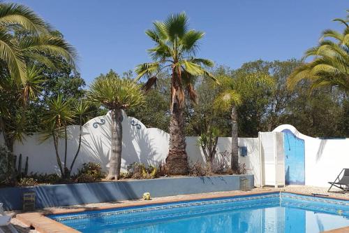 una piscina con palmeras y una valla en Quinta Do Grilo, en Amoreiras