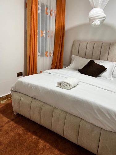 um quarto com uma cama grande e lençóis brancos em Ruyer one bedroom em Kisumu