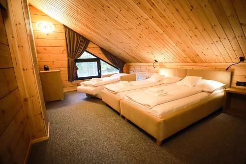 a bedroom with two beds in a wooden room at Vila Elis in Veľká Lomnica