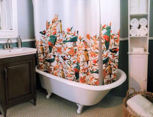 a bath tub with a shower curtain with birds on it at Cozy cottage near downtown Prescott in Prescott