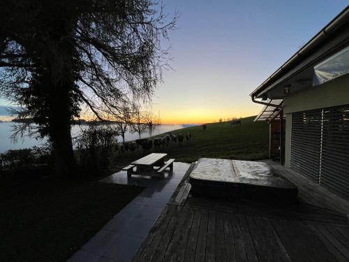 a bench sitting on a deck next to a lake at Maison chez Louis in Asuel