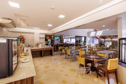 a restaurant with tables and chairs and a cafeteria at Tonello Business Hotel in Campo Mourão
