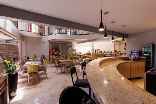 a restaurant with a bar and tables and chairs at Tonello Business Hotel in Campo Mourão
