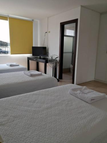a room with two beds and a desk with a computer at Hotel Yurak in Archidona