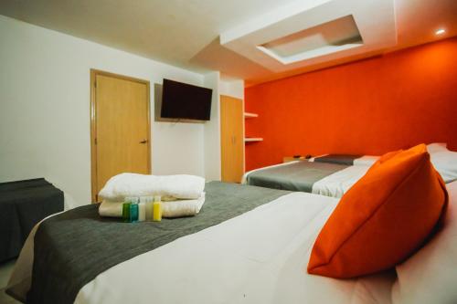 a hotel room with two beds with orange walls at Hotel Plaza 43 in Barranquilla