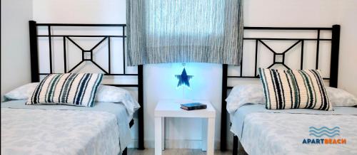 a bedroom with two beds and a table with a night stand at APARTBEACH LA CALETA CLIMA y VISTAS CALA CRANCS in Salou