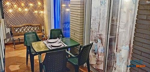 a table with green chairs and a plate of food on it at APARTBEACH LA CALETA CLIMA y VISTAS CALA CRANCS in Salou