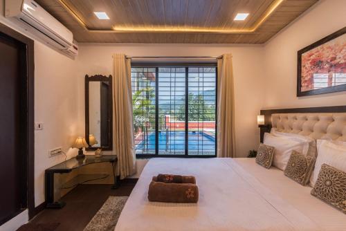 um quarto com uma cama grande e uma janela grande em SaffronStays Olive Greens, Karjat em Karjat