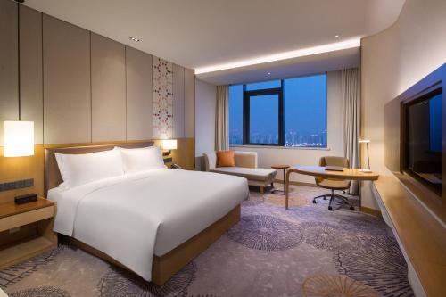 a hotel room with a bed and a television at Holiday Inn Tianjin Xiqing by IHG in Tianjin