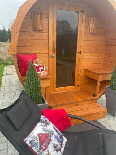 a teddy bear sitting in the front of a wooden cabin at Leśna Osada -Dominikowo -sauna , balia in Dominikowo