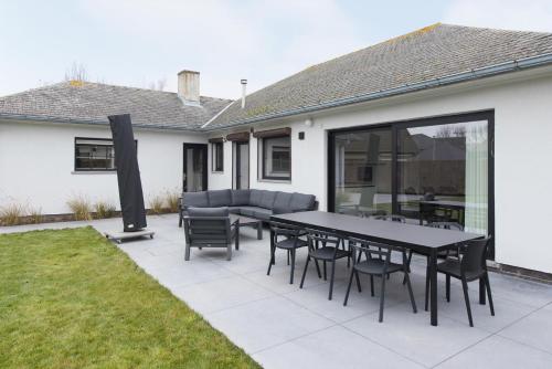 a patio with a table and chairs and a couch at Villa Stijn in Middelkerke