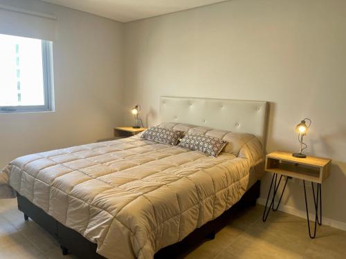 a bedroom with a large bed with two tables at Rent a Flat - Río Cuarto in Río Cuarto