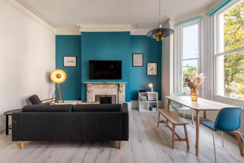 a living room with a black couch and a blue wall at Central 2BR Modern Apartment 5mins to train station in Brighton & Hove